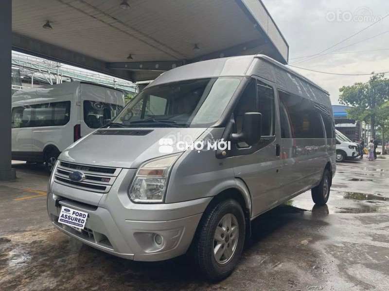 Ford Transit van 6 chỗ bạc.